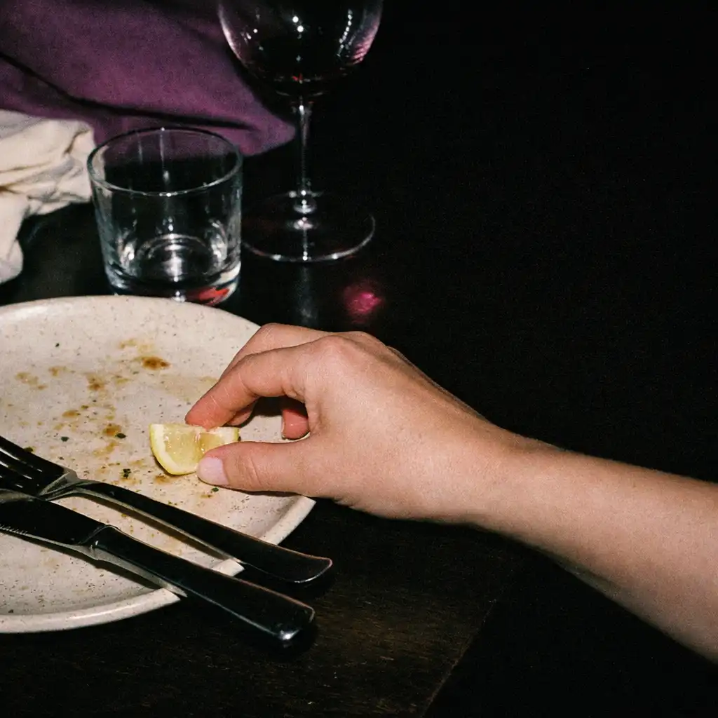 Detail keramického talíře, příboru a ruky při pozdním restauračním servisu